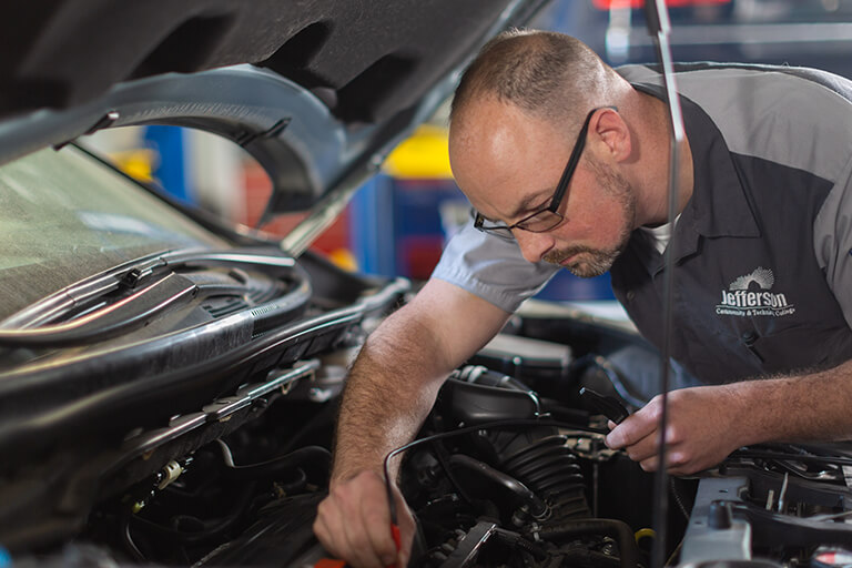 a man working on a car with the hood up