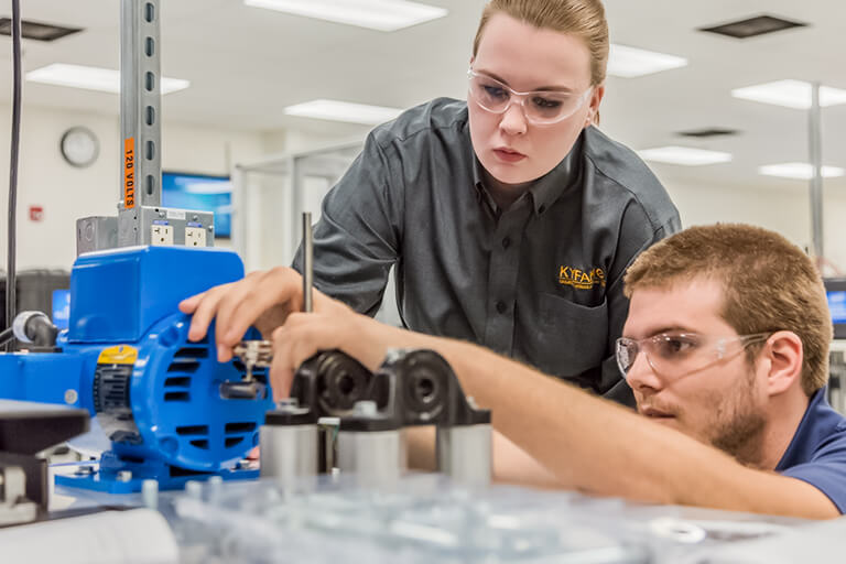 a man working with a machine and a woman observing him