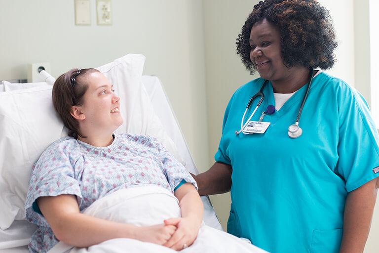 a nurse comforting a patient in a hospital bed