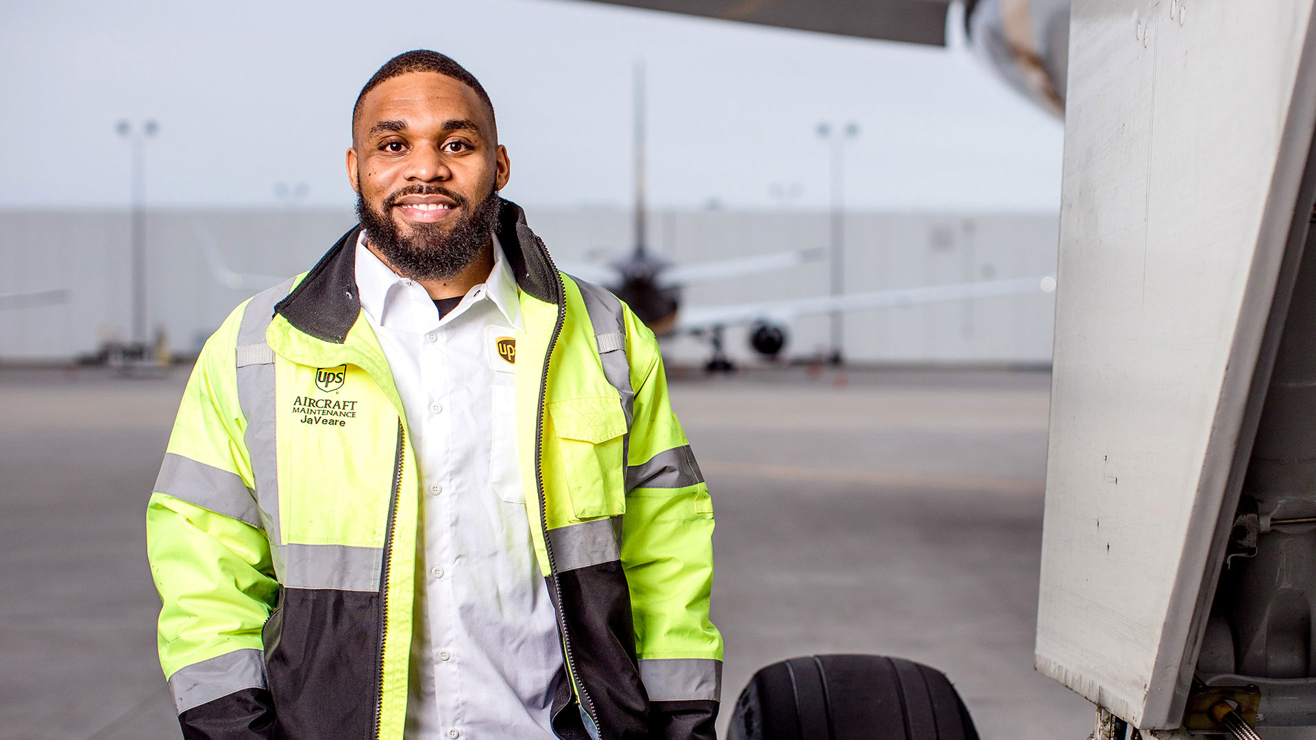 Man standing by a plane looking and smiling at camera