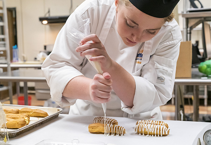 student drizzling sauce onto a plate